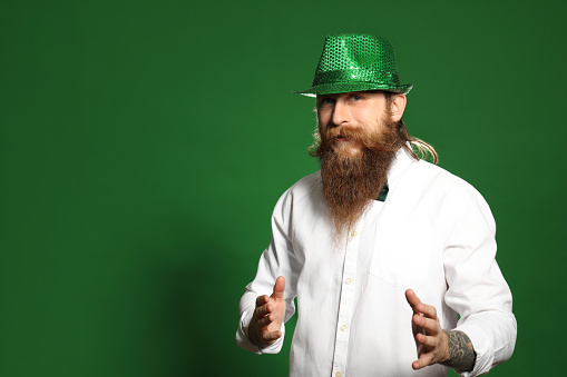 Bearded man in green hat on color background, space for text. St. Patrick's Day celebration