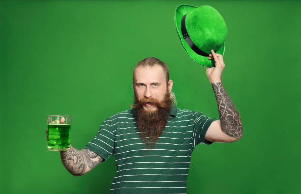 homem barbudo com cerveja verde no fundo colorido. celebração do dia de são patrício - beer glass mustache beer color image - fotografias e filmes do acervo