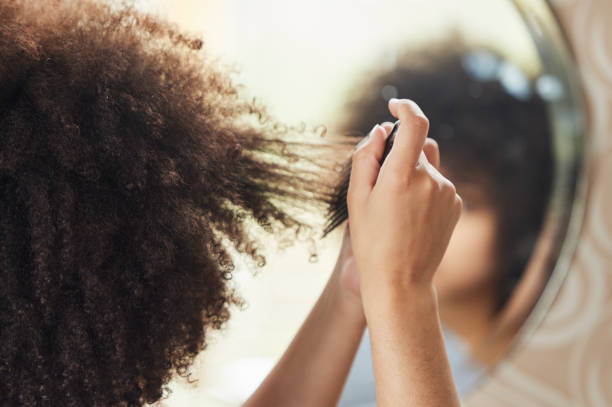 foto retrovisor de una mujer irreconocible mirándose al espejo mientras se aplica el maquillaje en casa - hair care combing women human hair fotografías e imágenes de stock