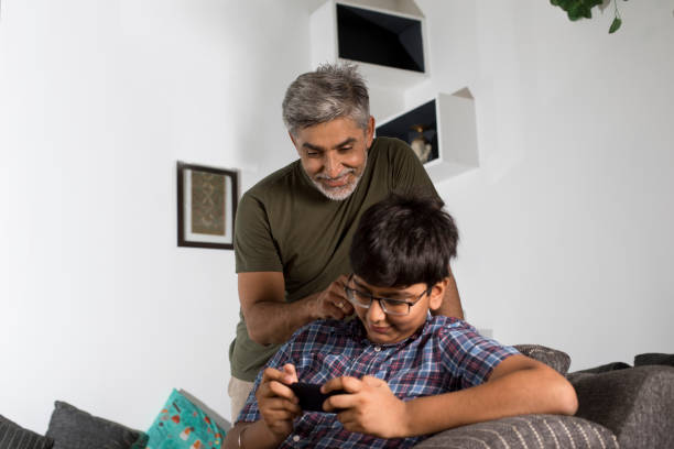 istock Father and son using mobile phone at home 1335221988