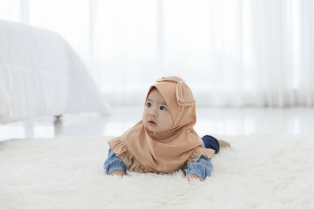 Baby crawling on the floor Baby girl 6 months crawling on the floor in the bedroom. Children Asian in hijab clothing pics of a cute muslim outfits stock pictures, royalty-free photos & images