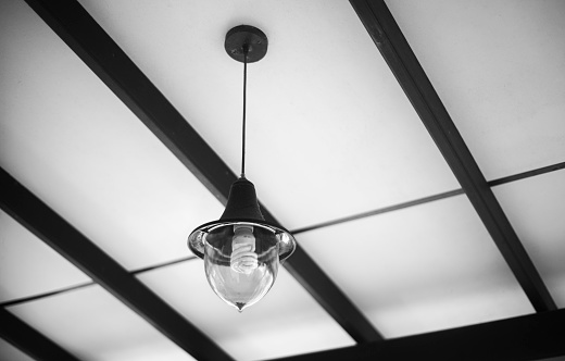 Hanging ceiling light bulb view from below. Modern living room black and white themed.