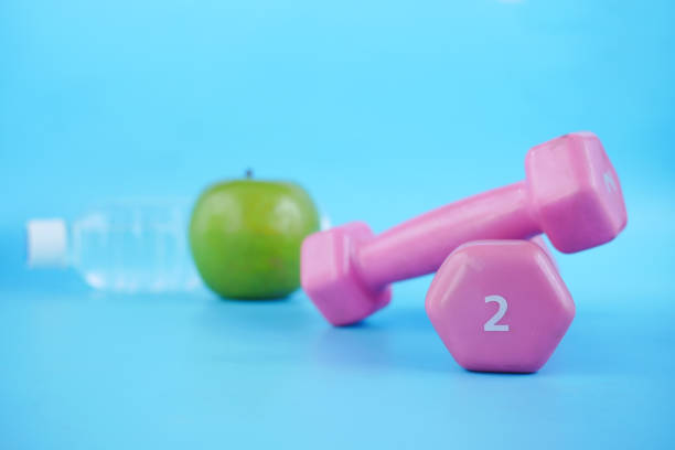 istock fresh drinking water, apple and a pink color dumbbell on table 1335233576
