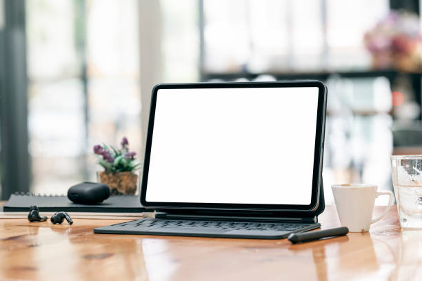 istock Mockup blank screen tablet with keyboard on wooden table in cafe room. 1335233648