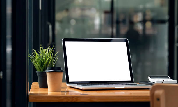 istock Mockup blank screen laptop computer on wooden table in dark tone office room. 1335233803