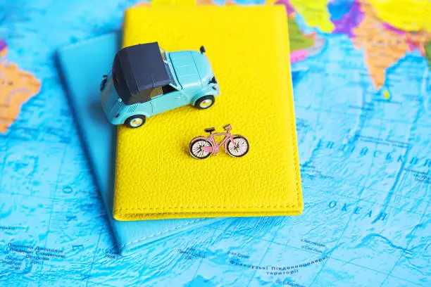 Photo of retro car and bicycle on colorful world map, passport