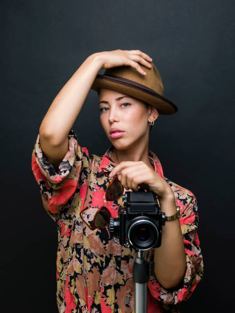 istock Young beautiful woman posing with a medium format film camera, studio shot 1335236773
