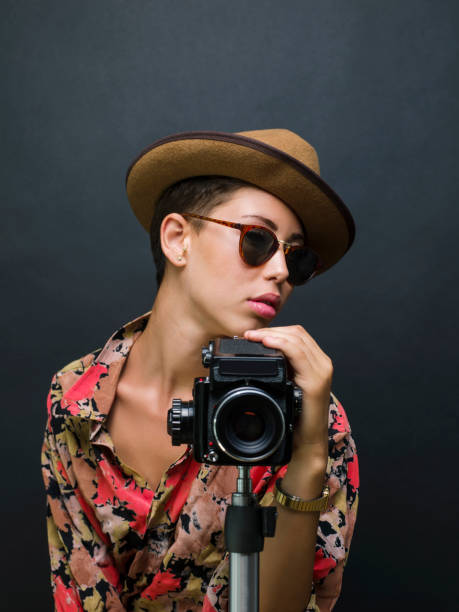istock Young beautiful woman posing with a medium format film camera, studio shot 1335236802