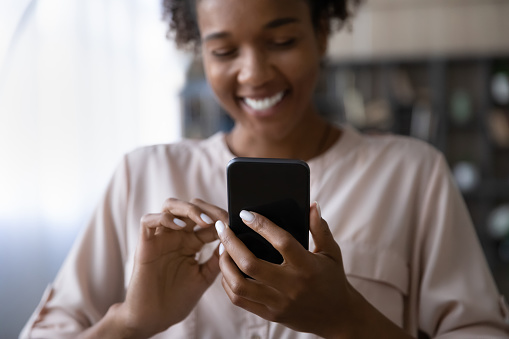 Crop close up focus of smiling African American woman use cellphone talk speak on video call on gadget. Happy ethnic female hold gadget text message on smartphone or have webcam digital event.