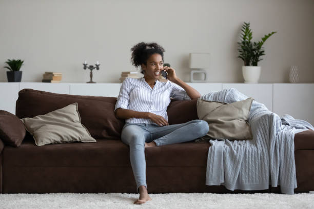 istock Smiling ethnic woman talk on cellphone at home 1335240397