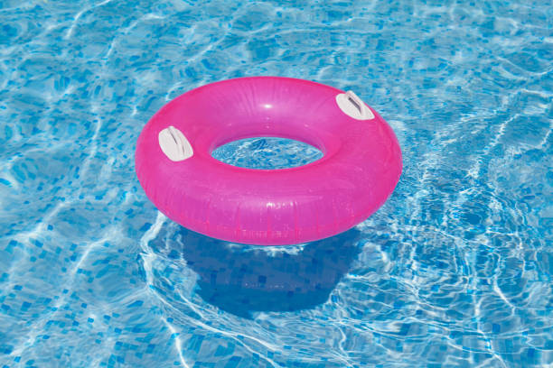 istock Pink Inflatable ring floating in swimming pool.  Clear blue water, waves 1335241538