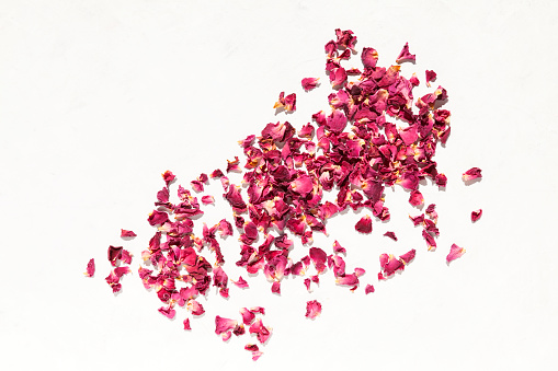 Dried rose petals on light background. Top view, space for text
