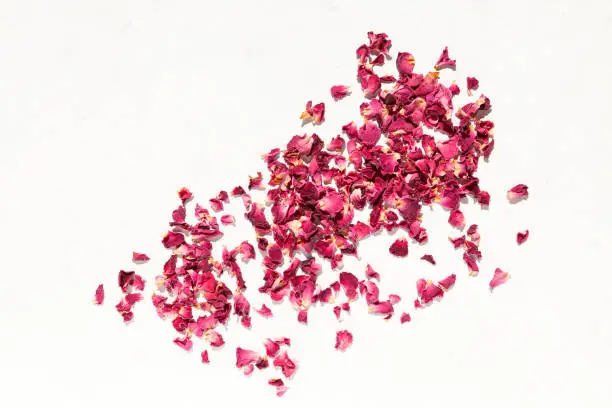 Dried rose petals on light background. Top view, space for text.