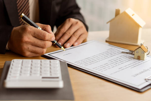 istock A home agent sitting at a desk in the office with a house plan with contract documents and a home buying idea, insurance or real estate loan idea calculator. 1335241649
