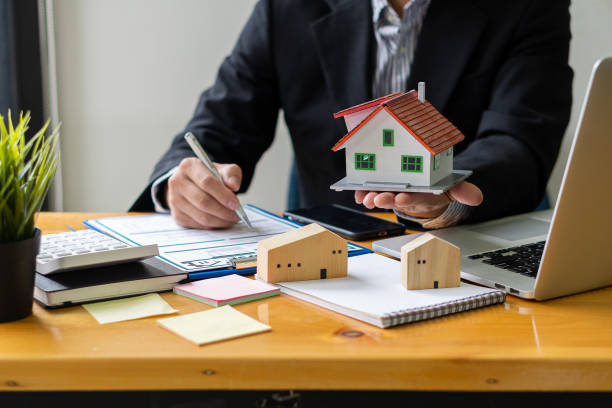 istock A home agent sitting at a desk in the office with a house plan with contract documents and a home buying idea, insurance or real estate loan idea calculator. 1335241652