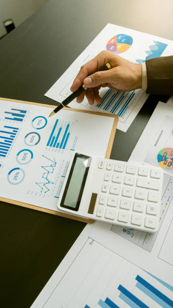 Businessman working with graph papers and laptop calculator to calculate company financial results. On a wooden table in offices and businesses, tax, accounting, statistics and vertical analytical research concepts. Businessman working with graph papers and laptop calculator to calculate company financial results. On a wooden table in offices and businesses, tax, accounting, statistics and vertical analytical research concepts. money memo stock pictures, royalty-free photos & images