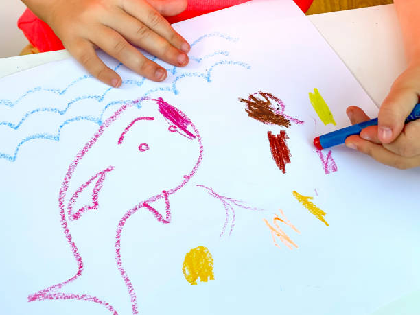 istock Yong child using coloured crayons to draw a  picture 1335242306