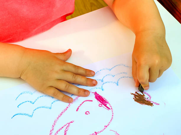 istock Yong child using coloured crayons to draw a  picture 1335242309