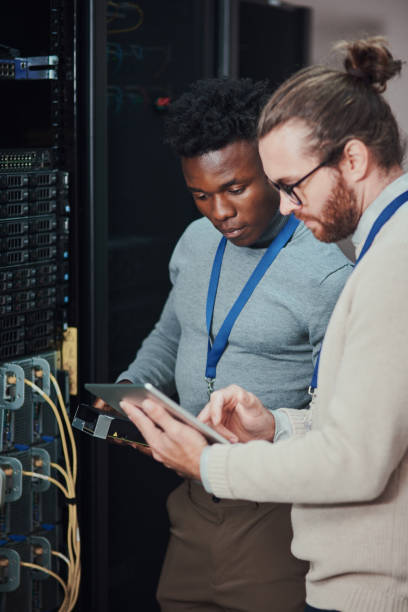 istock Shot of two young technicians using a digital tablet in a server room 1335243525