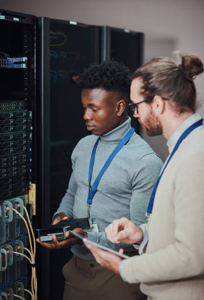 istock Shot of two young technicians working in a server room 1335243529