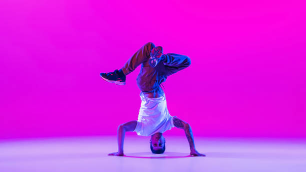 istock One young stylish man, break dancing dancer training in modern clothes isolated over bright magenta background at dance hall in neon light. 1335243804