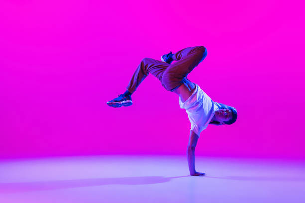 istock One young stylish man, break dancing dancer training in modern clothes isolated over bright magenta background at dance hall in neon light. 1335243805