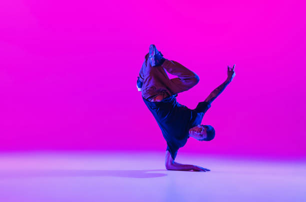 istock One dancing man, break dancer in action, motion in modern clothes isolated over bright magenta background at dance hall in neon light. 1335243818
