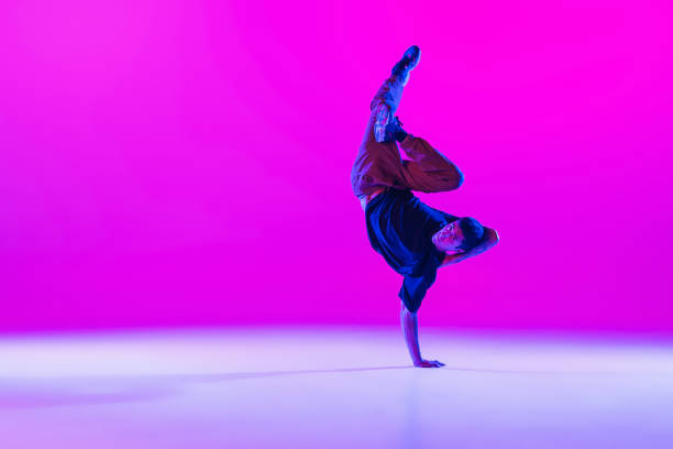 istock One dancing man, break dancer in action, motion in modern clothes isolated over bright magenta background at dance hall in neon light. 1335243831