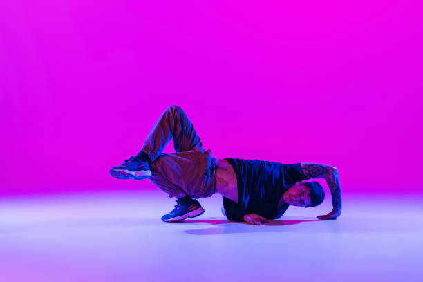 istock Modern dance style. Hip hop, break dancing dancer in action, motion in dark clothes isolated over bright magenta background at dance hall in neon light. 1335243842