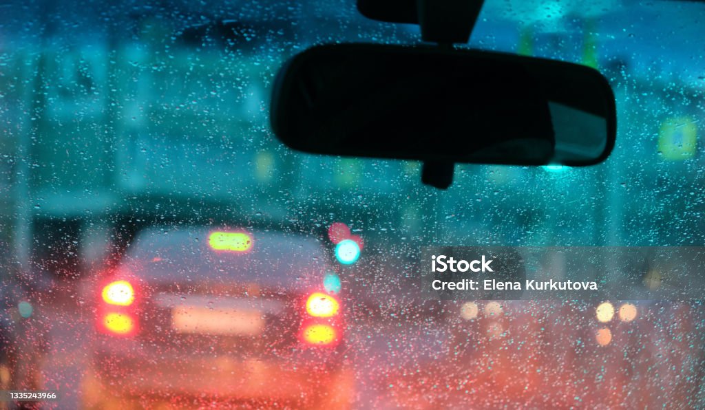 Motion blurred night city lights illuminated streets through  fogged up in small drops  car windshield Window Stock Photo