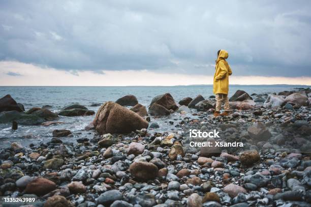 Woman Wearing Yellow Raincoat Walking On The Beach On A Rainy Day Stock Photo - Download Image Now