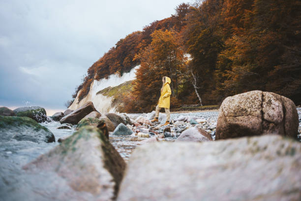 Woman wearing yellow raincoat walking on the beach on a rainy day Woman wearing yellow raincoat walking on the beach on a rainy day baltic sea people stock pictures, royalty-free photos & images