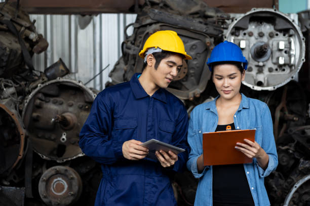 Group of young Asian male and female employee worker using clipboard checking old automotive spare parts, engine, motor, machine at the garage industry factory or automotive spare parts warehouse grupo de jóvenes trabajadores asiáticos empleados que utilizan el portapapeles que revisa las piezas de repuesto automotrices antiguas, el motor, el motor, la máquina en la fábrica de la industria del garaje o el almacén de piezas de repuesto automotr
