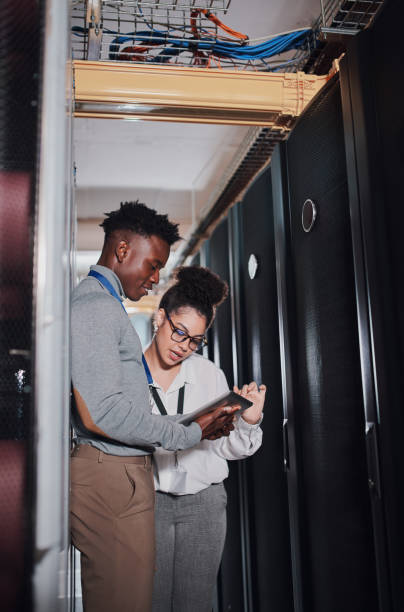 plan de deux jeunes techniciens utilisant une tablette numérique dans un centre de données - data center computer programmer women photos et images de collection