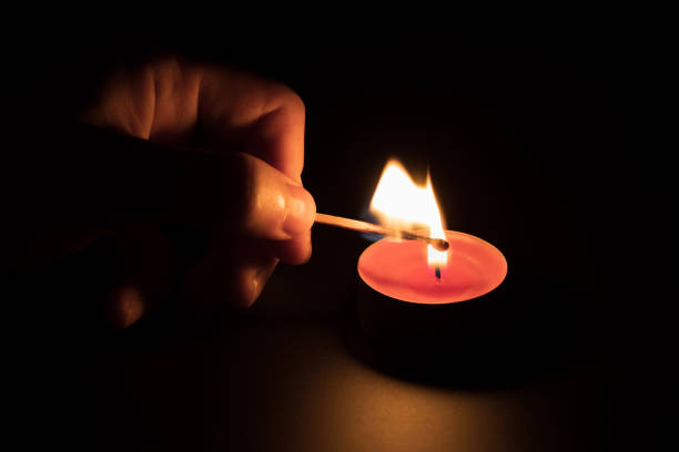 istock Lighting a red candle with a match in the dark. Memory concept. Black background. 1335249161