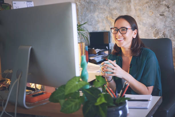 istock Shot of a young woman sitting and enjoying a cup of coffee while using her computer to work from home 1335249675