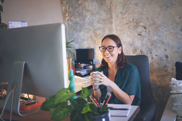 istock Shot of a young woman sitting and enjoying a cup of coffee while using her computer to work from home 1335249681