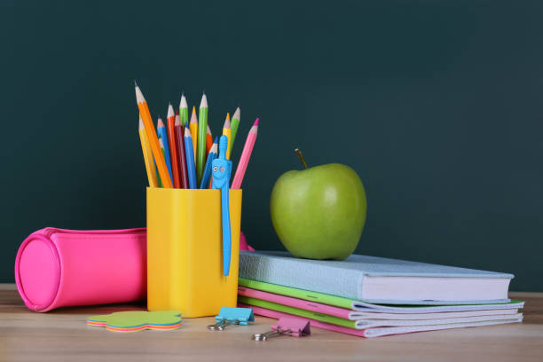 istock Composition with stationery and apple on table near chalkboard. Doing homework 1335251309