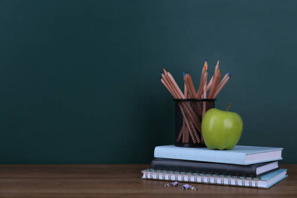 istock Composition with stationery and apple on table near chalkboard, space for text. Doing homework 1335251377
