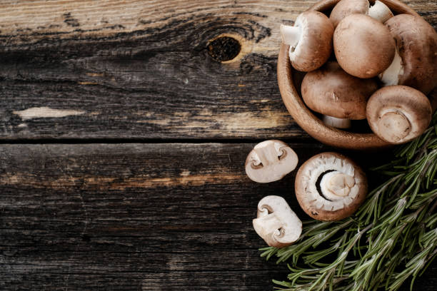 istock Brown champignon mushrooms on old dark wooden background. 1335252371