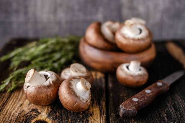 istock Brown champignon mushrooms on old dark wooden background. 1335252428