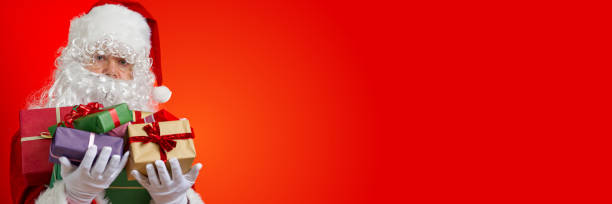 istock Happy Santa Claus with gift boxes in hands on red background with copy space 1335252567