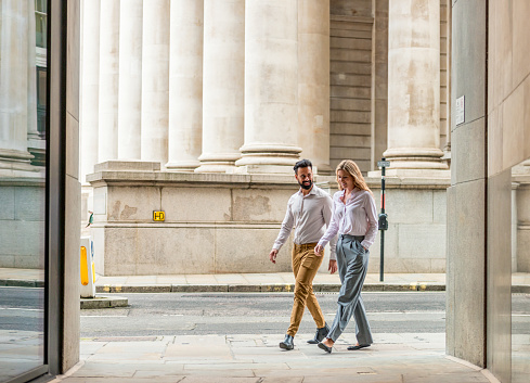 Two colleagues chatting as they walk on a street in London's financial district.