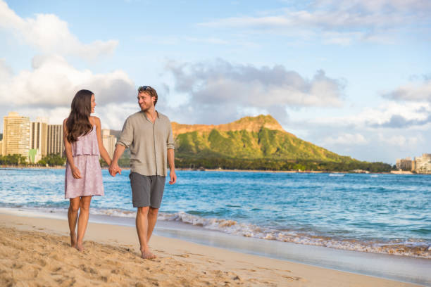 pareja caminando en la playa de waikiki vacaciones en hawai. feliz pareja enamorada relajándose al atardecer en un famoso destino turístico en honolulu, oahu, hawái - waikiki beach fotografías e imágenes de stock