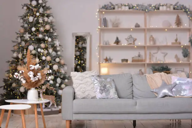 Photo of Christmas modern living room with Christmas tree, sofa, shelf with Christmas decorations. Happy new year and merry christmas