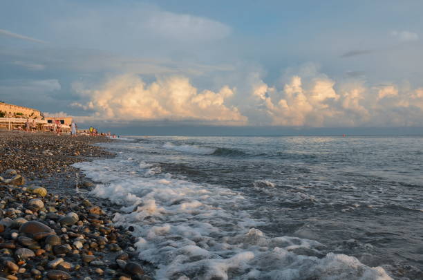 Clouds during sunset and surf on the beach with pebbles in the village of Loo Krasnodar Territory