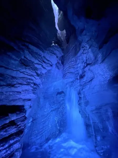 Photo of waterfall in cave with colored lights cascate del varone