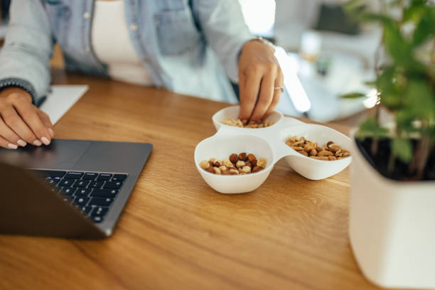 istock Healthy eating and working. Woman eating nuts while working on laptop. 1335261982