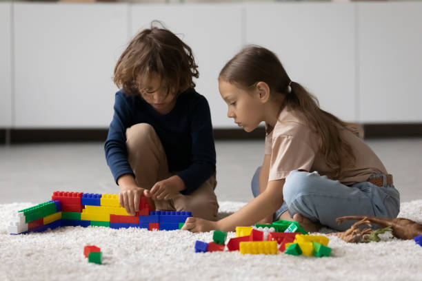 istock Focused little boy and girl playing construction toys, completing model 1335262740