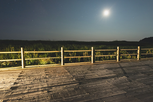 A beach boardwalk beneath the Moon on a Summer night. Long exposure.